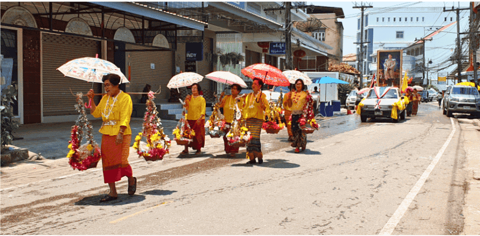 Vrouwen in traditionele Thaise kleding vieren Songkran met water en bloemenparade.