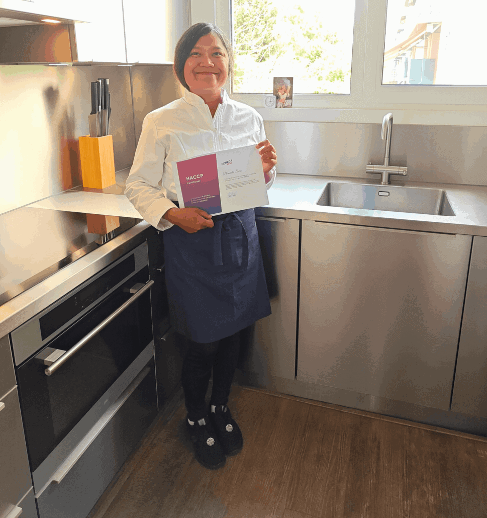 Vrouw met HACCP-certificaat in keuken voor veilige Thaise catering.