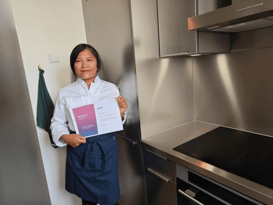Vrouwelijke chef-kok met certificaat in een moderne keuken.