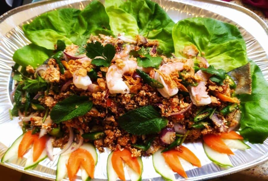 Verse Thaise salade met garnalen en groenten op een zilveren schaal.