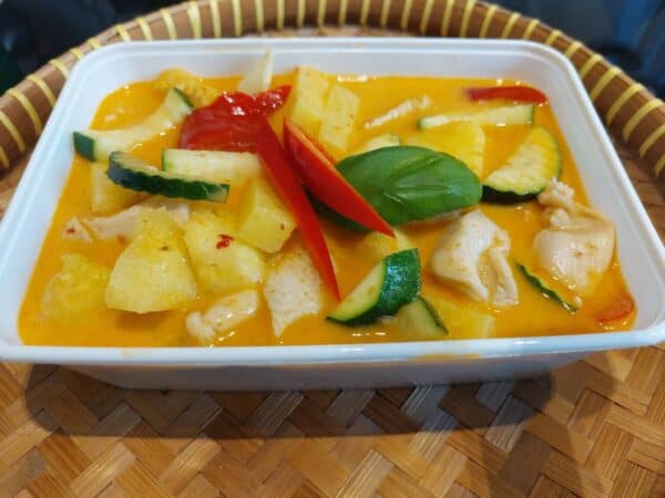 Authentieke Thaise groene curry met kip en verse groenten in een witte schaal.