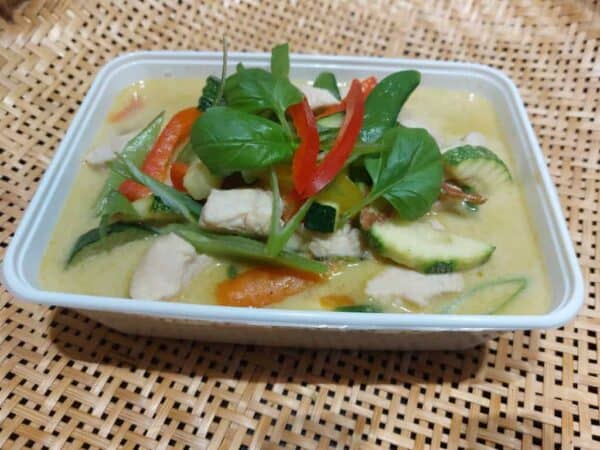 Verse curry met groenten en kip in een witte schaal.