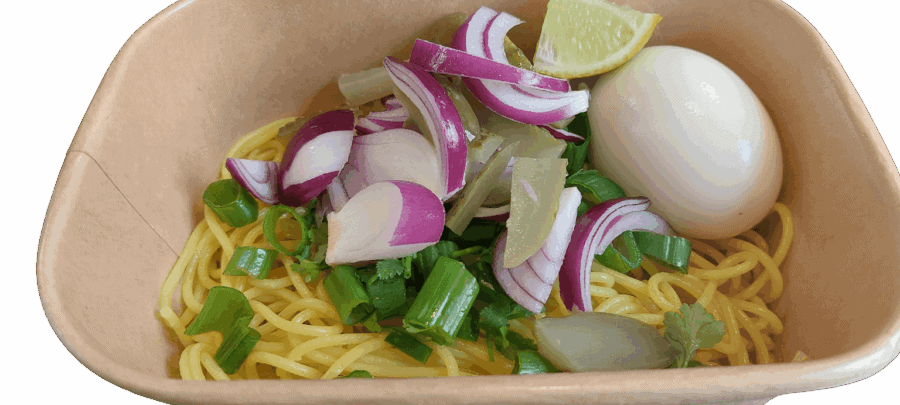 Verse Aziatische noedelsoep met ei, lente-ui en limoen in papieren bakje.