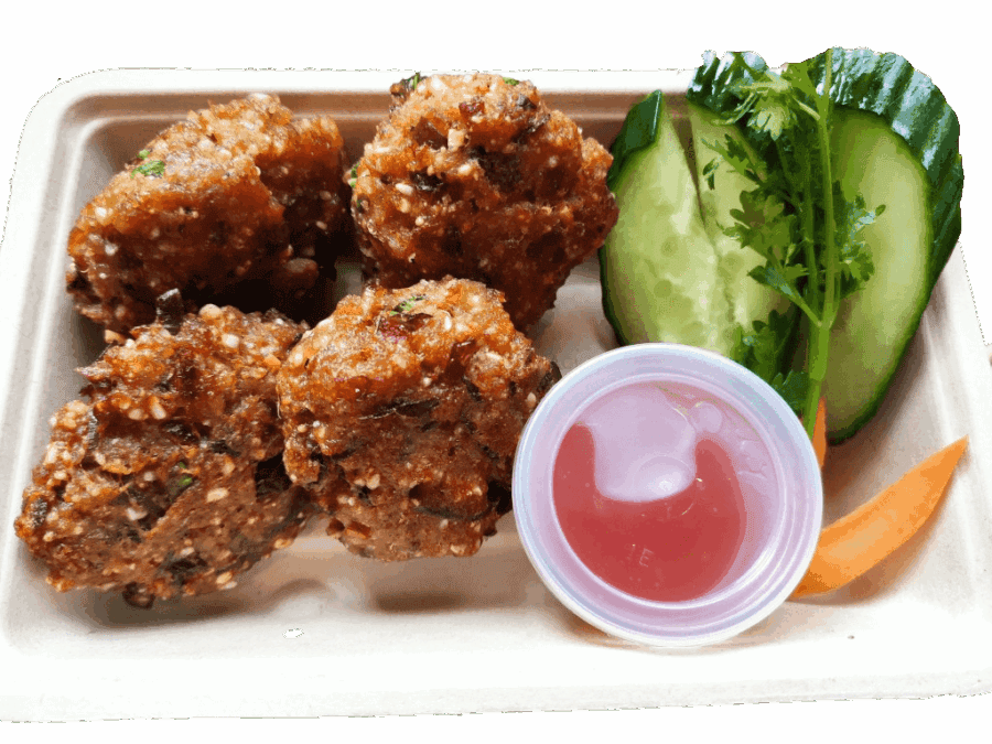 Thai fried chicken nuggets met verse komkommer en dipsaus.