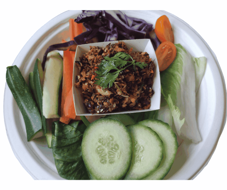 Verse Thaise groenten en gekruid vlees op een wit bord.