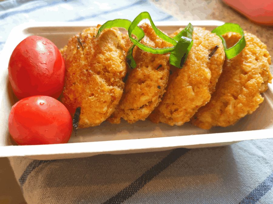 Thai fried chicken with green peppers and cherry tomatoes in a white dish.